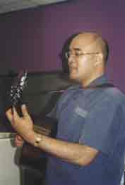 Photo shows a maori man playing a guitar. 